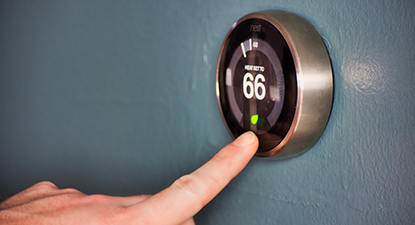 Hand operating smart thermostat to save money