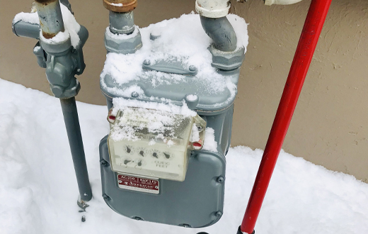 A gas meter is cleared of snow.